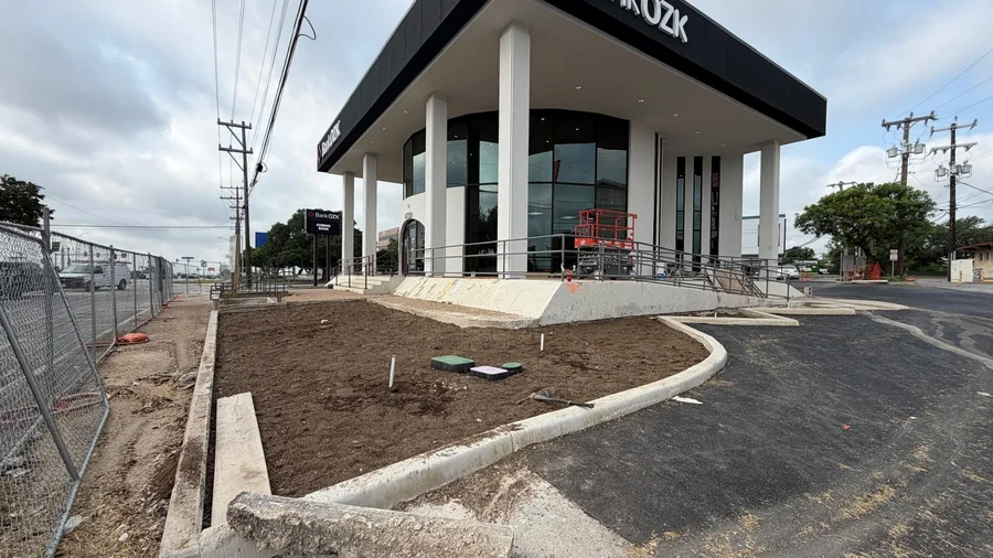 Finished landscape beds wrapping a commercial building entrance and parking lot in San Antonio