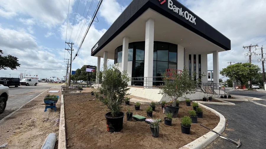 Trimmed shrubs and canopy trees framing a commercial entrance, the arrival view that drives apartment curb appeal San Antonio renters notice first