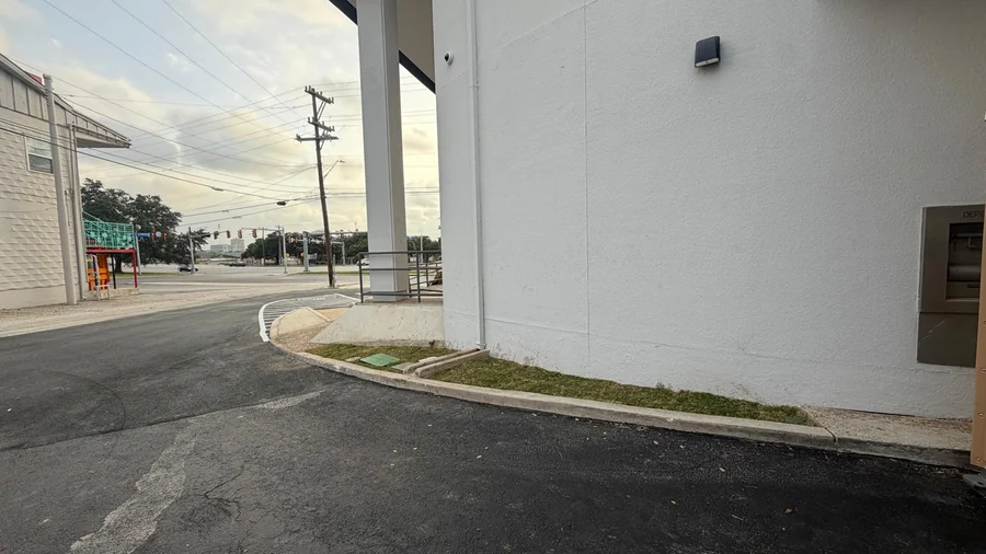 Curbed landscape bed running beside a commercial walkway in San Antonio